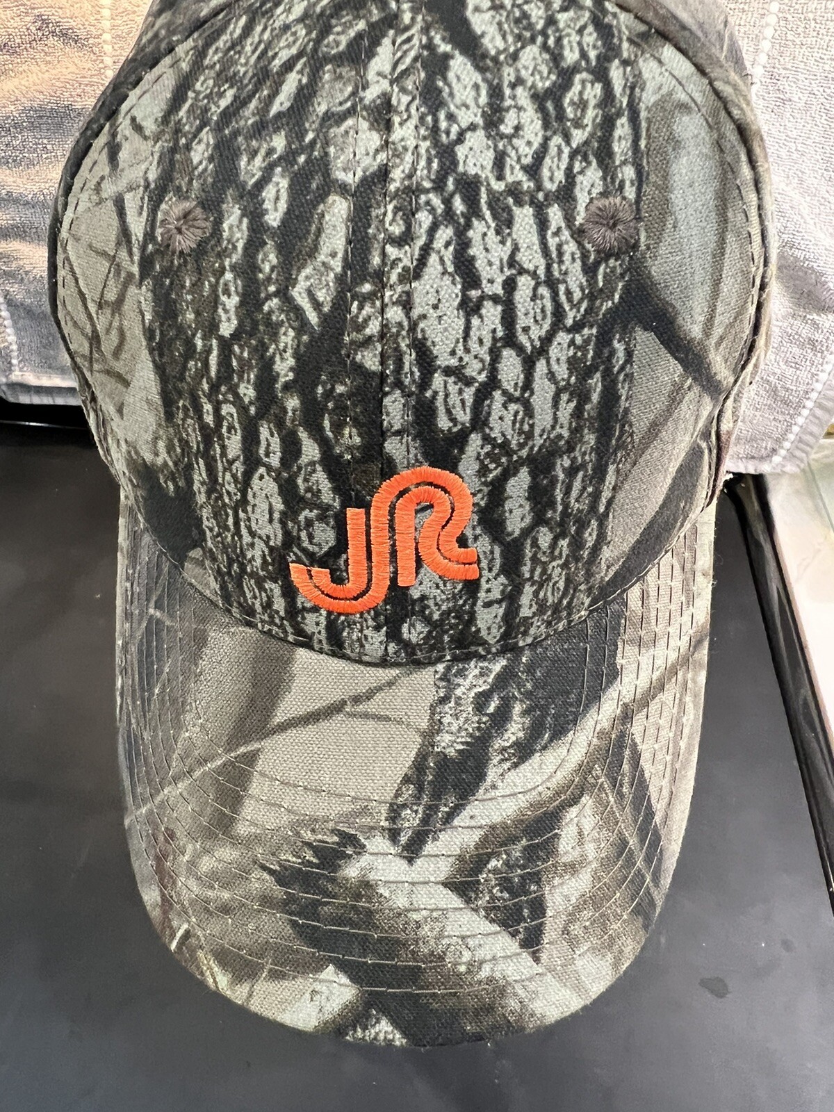 Realtree Hardwoods Camouflage Hat with orange Embroidered Logo on Front. EUC Adj