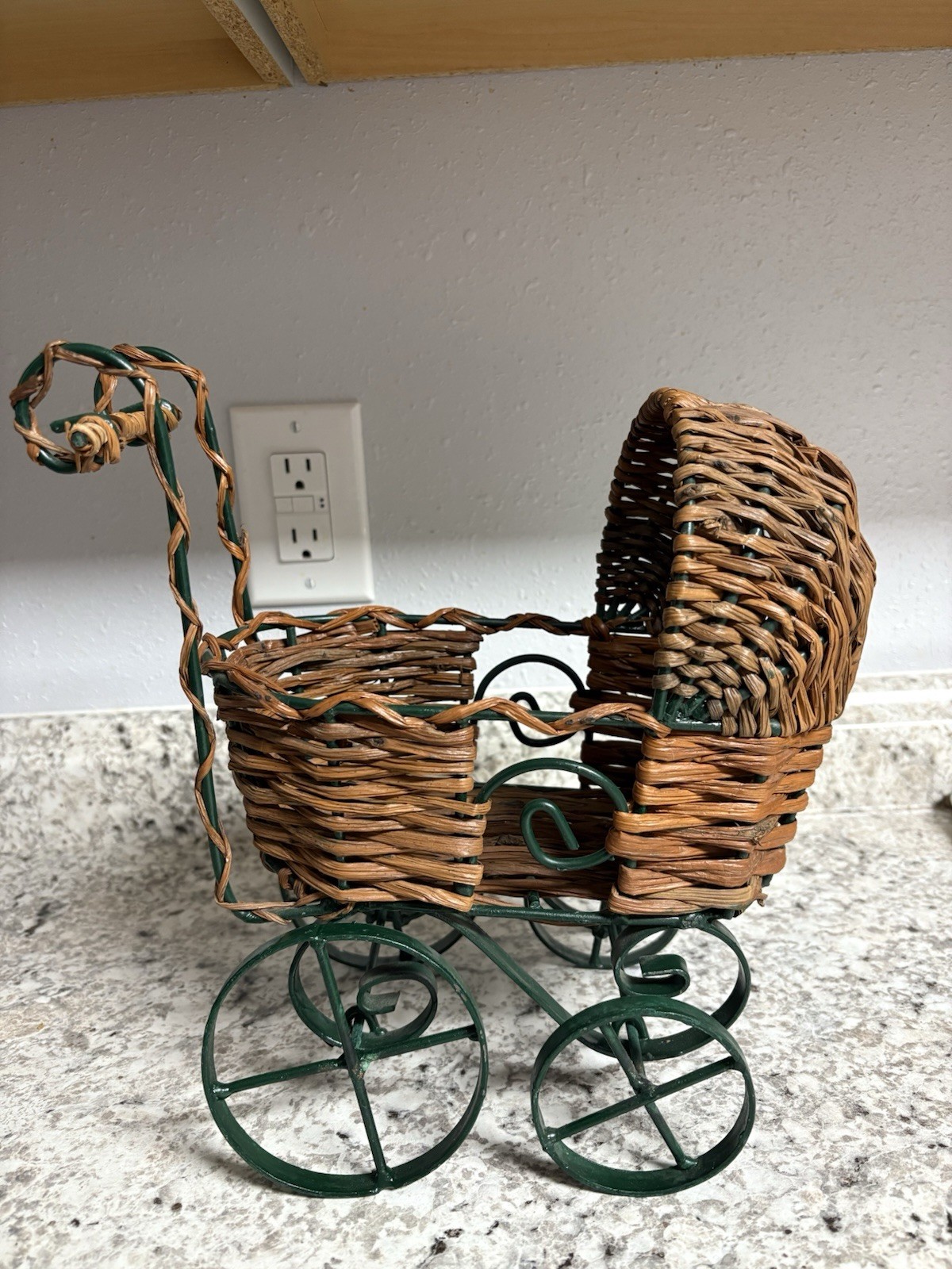 Vintage wicker doll carriage/stroller with a green iron frame/wheels.  