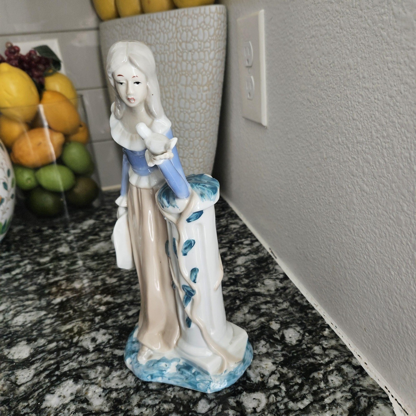 Vintage porcelain figurine lady holding a white bird leaning on a pedestal
